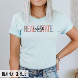 Peut inclure: Un t-shirt bleu clair avec le texte "REAL ESTATE agent" en lettres color&eacute;es. Le texte est dans un style de police moderne.