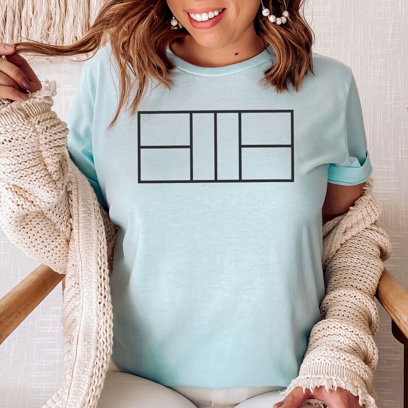 May include: A light blue t-shirt with a black outline of a tennis court on the front.