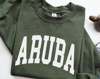May include: Military green sweatshirt with the word "ARUBA" in bold white letters. The sweatshirt is a crew neck style and is made of a soft material. The text "MILITARY GREEN" is at the bottom of the image.