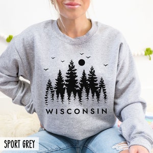 May include: A gray sweatshirt with a black print of a forest scene with a moon and birds. The text "WISCONSIN" is printed below the forest scene.