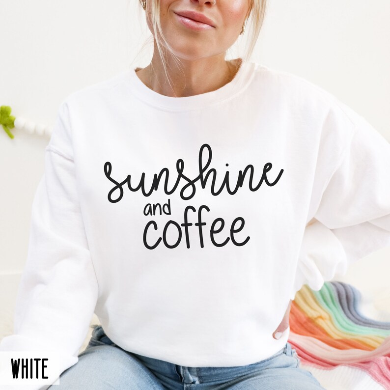 May include: White sweatshirt with the text "sunshine and coffee" in black script.