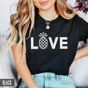 May include: Black t-shirt with a white pineapple graphic and the word "LOVE" in white letters.
