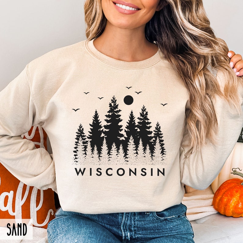 May include: A beige sweatshirt with a black graphic of a forest silhouette and the word "WISCONSIN" printed on the front.