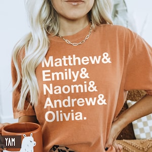 K&ouml;nnte beinhalten: Ein orangefarbenes T-Shirt mit wei&szlig;em Text, der "Matthew & Emily & Naomi & Andrew & Olivia." lautet.