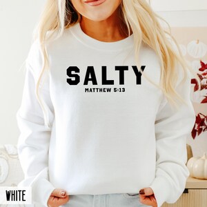 May include: White sweatshirt with black text that reads "SALTY" and "MATTHEW 5:13".