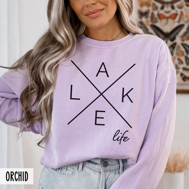 May include: A lavender long-sleeved sweatshirt with a black graphic design that says "LAKE life" with the letters in a criss-cross pattern.