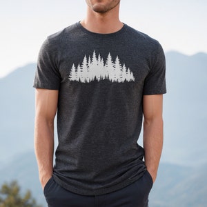 May include: A dark heather grey t-shirt with a white silhouette of a forest on the front.