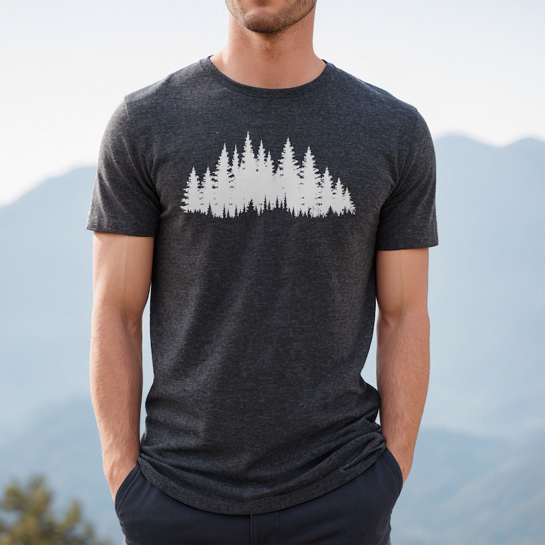 May include: A dark heather grey t-shirt with a white silhouette of a forest on the front.