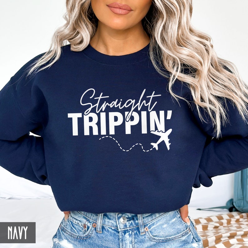 Puede incluir: Sudadera azul marino con texto blanco que dice "Straight Trippin'" y un gr&aacute;fico de avi&oacute;n blanco.