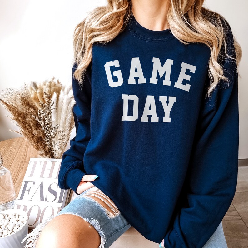 May include: A navy blue sweatshirt with the text "GAME DAY" in white lettering.