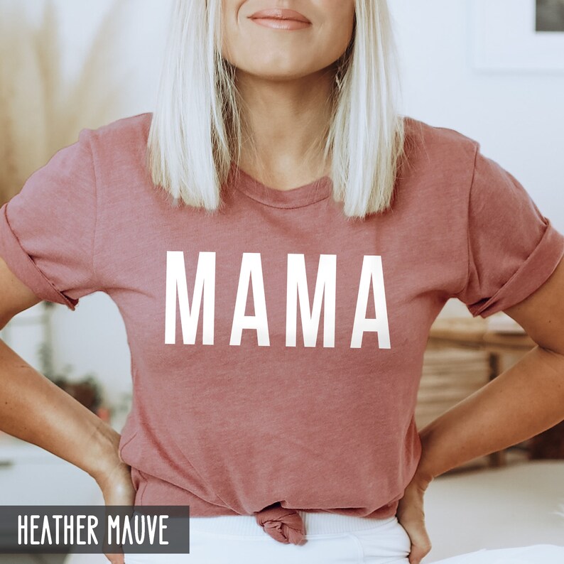 May include: A heather mauve t-shirt with the word "MAMA" printed in white on the front.