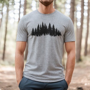 May include: A heather grey t-shirt with a black silhouette of a forest on the front.