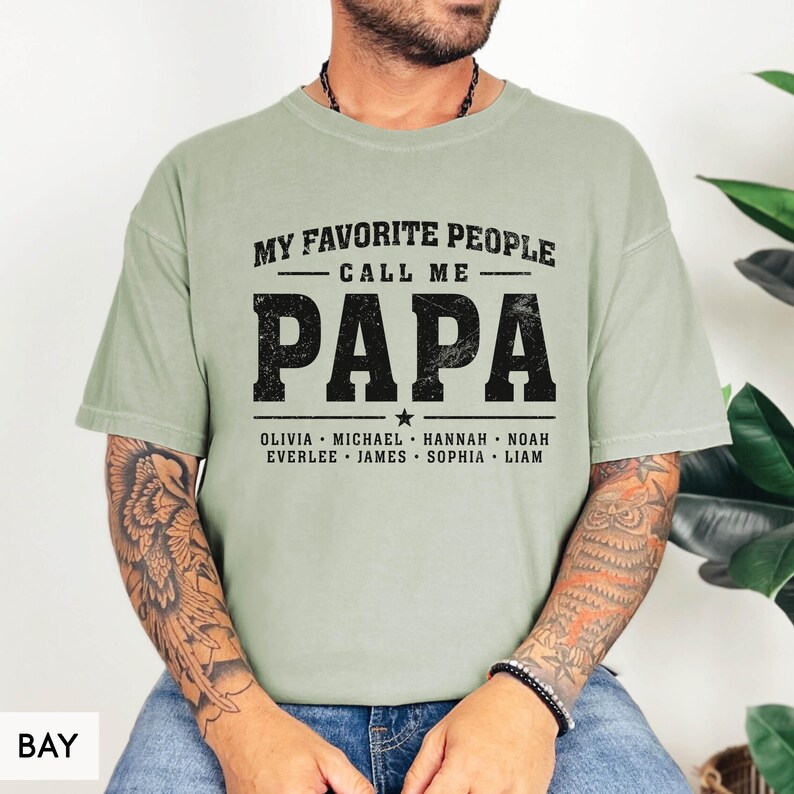 A man wearing a green t-shirt with the text "MY FAVORITE PEOPLE CALL ME PAPA" printed on it.