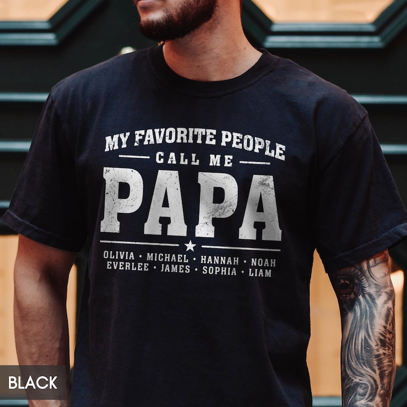 A man wearing a black t-shirt with the text "MY FAVORITE PEOPLE CALL ME PAPA" printed on it.