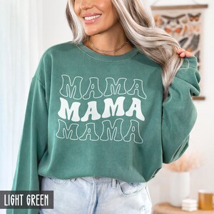 May include: A light green sweatshirt with the text "MAMA MAMA MAMA" in white.