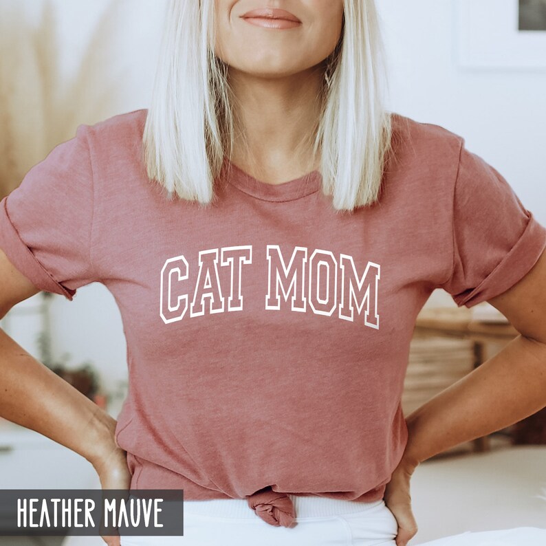 May include: A heather mauve t-shirt with the text "CAT MOM" in white outlined letters.