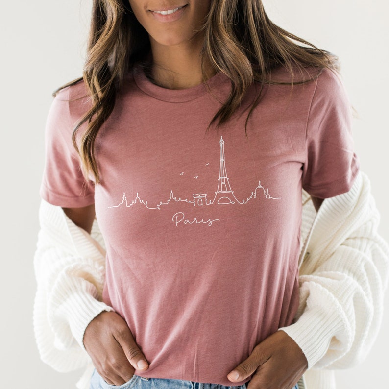 Op de afbeelding: Een mauve t-shirt met een witte omtrek van de Eiffeltoren en het woord "Paris" eronder.