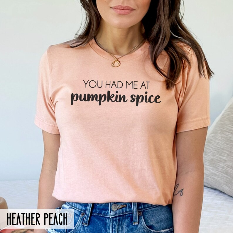 Pode incluir: Uma camiseta cor de p&ecirc;ssego com o texto "You had me at pumpkin spice" impresso em preto.