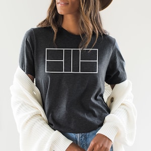 May include: A dark gray t-shirt with a white outline of a tennis court on the front.