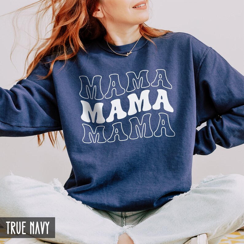 May include: A navy blue sweatshirt with the word "MAMA" repeated three times in a white retro font.
