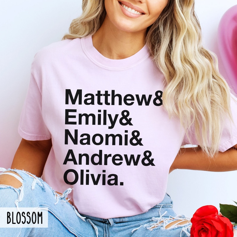 K&ouml;nnte beinhalten: Ein pinkfarbenes T-Shirt mit schwarzem Text, der "Matthew & Emily & Naomi & Andrew & Olivia." lautet.