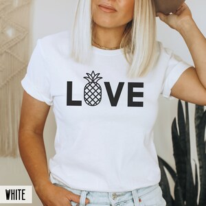 May include: White t-shirt with a black pineapple graphic and the word "LOVE" printed on the front.