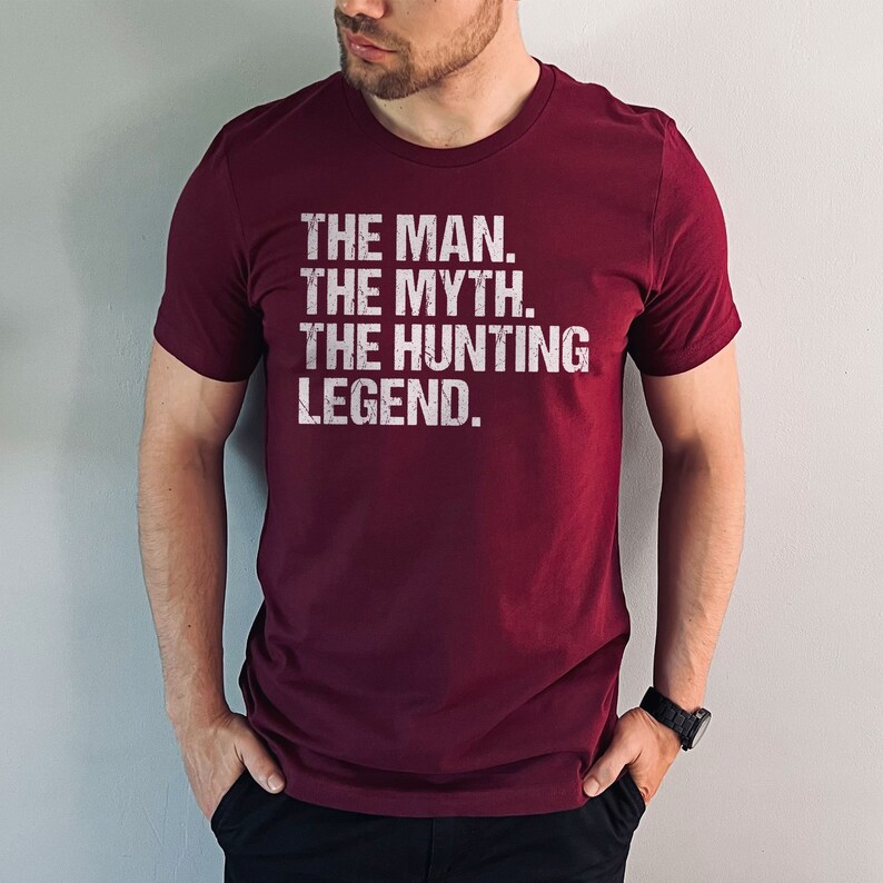 May include: A maroon t-shirt with white text that reads "THE MAN. THE MYTH. THE HUNTING LEGEND."