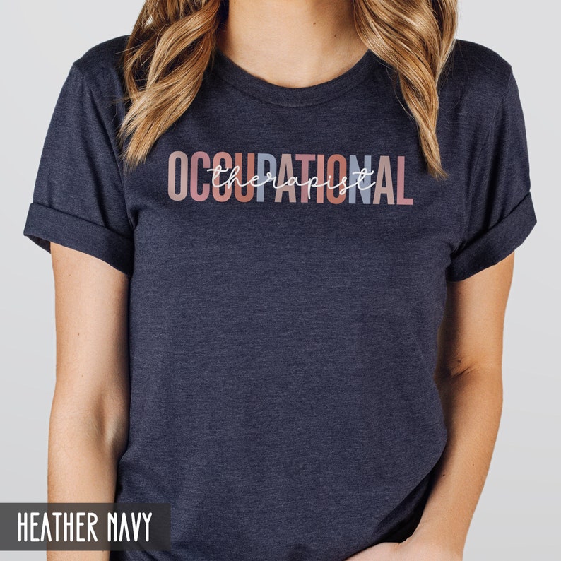 May include: A heather navy blue t-shirt with the text "OCCUPATIONAL therapist" in a rainbow color gradient.