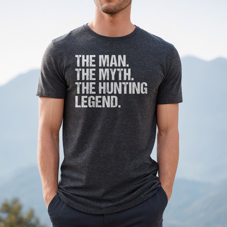 May include: A dark heather grey t-shirt with the text "THE MAN. THE MYTH. THE HUNTING LEGEND." printed in white.