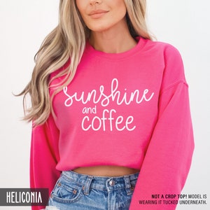 May include: Pink sweatshirt with the text "Sunshine and coffee" in white lettering.