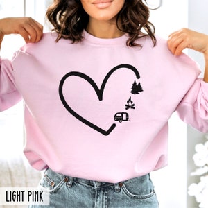 May include: A light pink sweatshirt with a black heart design. The heart is filled with a camper, a campfire, and trees. The text "LIGHT PINK" is at the bottom of the image.