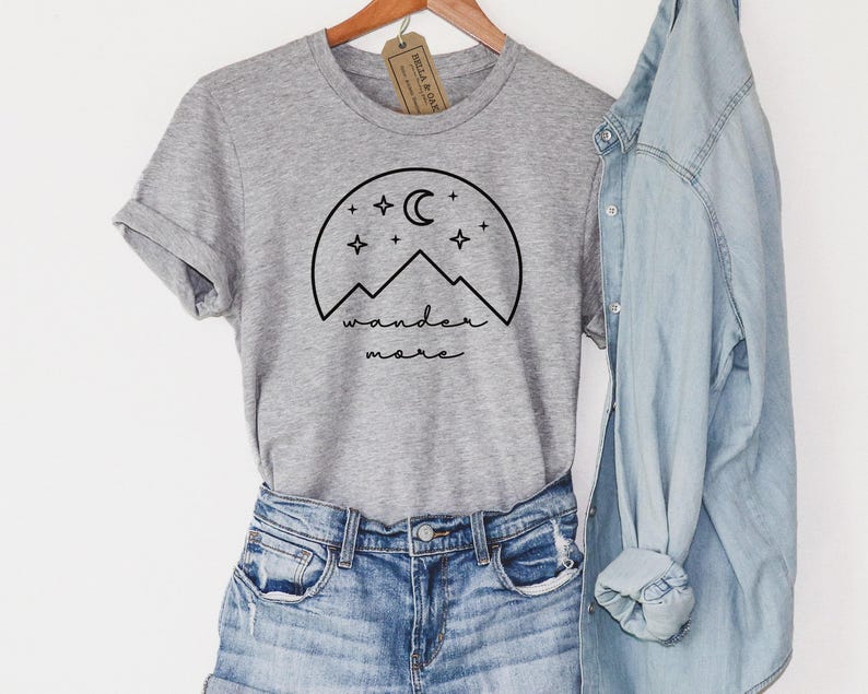 A heather gray t-shirt with a black mountain graphic is displayed alongside blue denim shorts and a light blue denim shirt.
