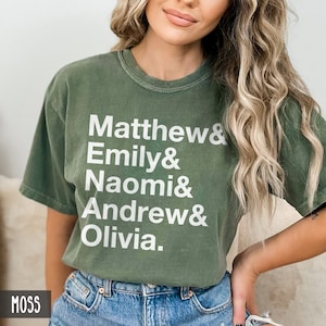 K&ouml;nnte beinhalten: Ein gr&uuml;nes T-Shirt mit wei&szlig;em Text, der "Matthew & Emily & Naomi & Andrew & Olivia." lautet.