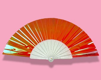 May include: A red and white iridescent folding fan. The fan is closed and has a white handle.