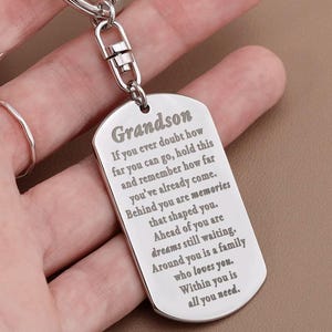 May include: A silver-toned metal dog tag keychain featuring an engraved message that reads: Grandson, If you ever doubt how far you can go, hold this and remember how far you've already come. Behind you are memories that shaped you. Ahead of you are dreams still waiting. Around you is a family who loves you. Within you is all you need.