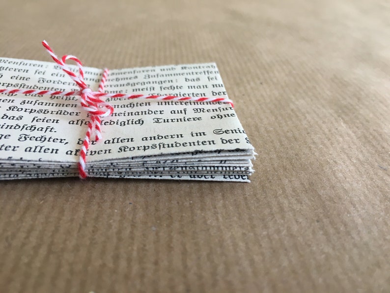 Puede incluir: Una pila de viejas p&aacute;ginas de papel blanco atadas con una cuerda roja y blanca. Las p&aacute;ginas est&aacute;n llenas de texto negro en una fuente tradicional. El texto dice: "Menfumen Ensamenturen unb Ronteah teren sei ein nemed Bufammentreffen bas fei eine Border Доганеgegan rpsstudenten Das hei&szlig;t, en zusammen -Korpsbr&uuml;der Nome: meist feite man nLA Aldebergierten der nachten untereinande neinander auf Mensur bas seien also lediglich Turniere ohne indschaft. e Fechter, der allen andern im Senin ter allen akiven Korpsstudenten der S"