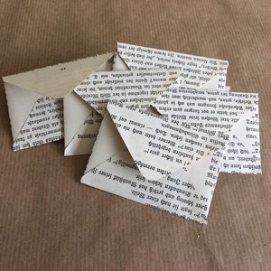 Puede incluir: Una pila de sobres de papel doblados hechos con p&aacute;ginas de libros reciclados. Los sobres est&aacute;n en blanco y listos para usar para enviar cartas o notas.