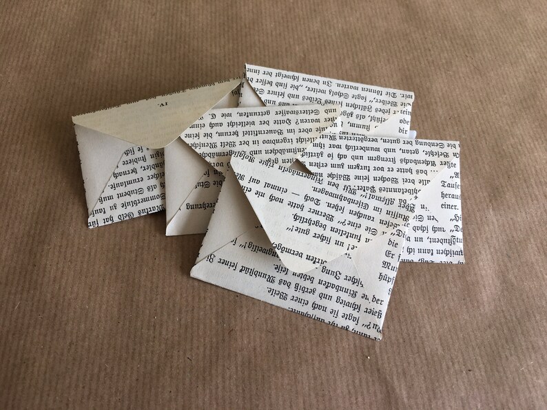 Puede incluir: Una pila de sobres de papel doblados hechos con p&aacute;ginas de libros reciclados. Los sobres est&aacute;n en blanco y listos para usar para enviar cartas o notas.