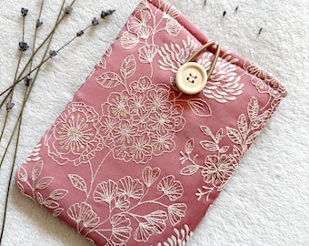 Puede incluir: Una bolsa de tela rosa con un patrón floral y un cierre de botón de madera. La bolsa es perfecta para guardar objetos pequeños como joyas, llaves o maquillaje.