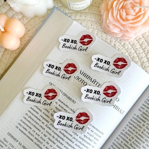 May include: Four white stickers with red lips and the text "XO XO, Bookish Girl" on a book.