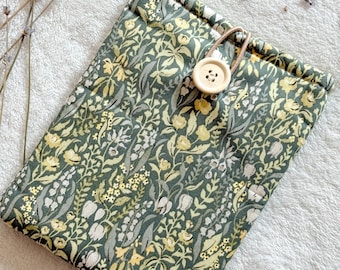 May include: A green fabric pouch with a floral pattern in yellow and white. The pouch has a drawstring closure and a wooden button.