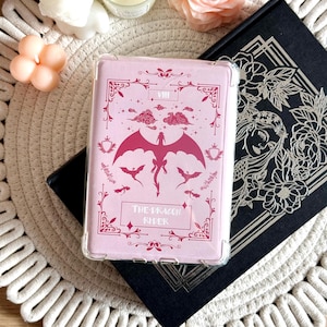 Könnte beinhalten: Eine rosa Handyhülle mit durchsichtiger Rückseite und einem roten Drachen-Design. Die Hülle hat einen dekorativen Rand mit dem Text "The Dragon Rider" und der Nummer "VIII".