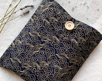 Könnte beinhalten: Eine schwarze Stofftasche mit einem goldenen Wolkenmuster und einem Verschluss aus Holz.