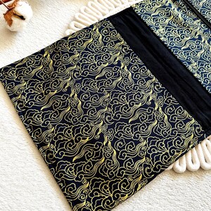 May include: Black zippered pouch with a gold cloud pattern. The pouch is made of fabric and has a zipper closure.