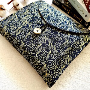 May include: A black fabric book cover with a gold cloud pattern and a single button closure.