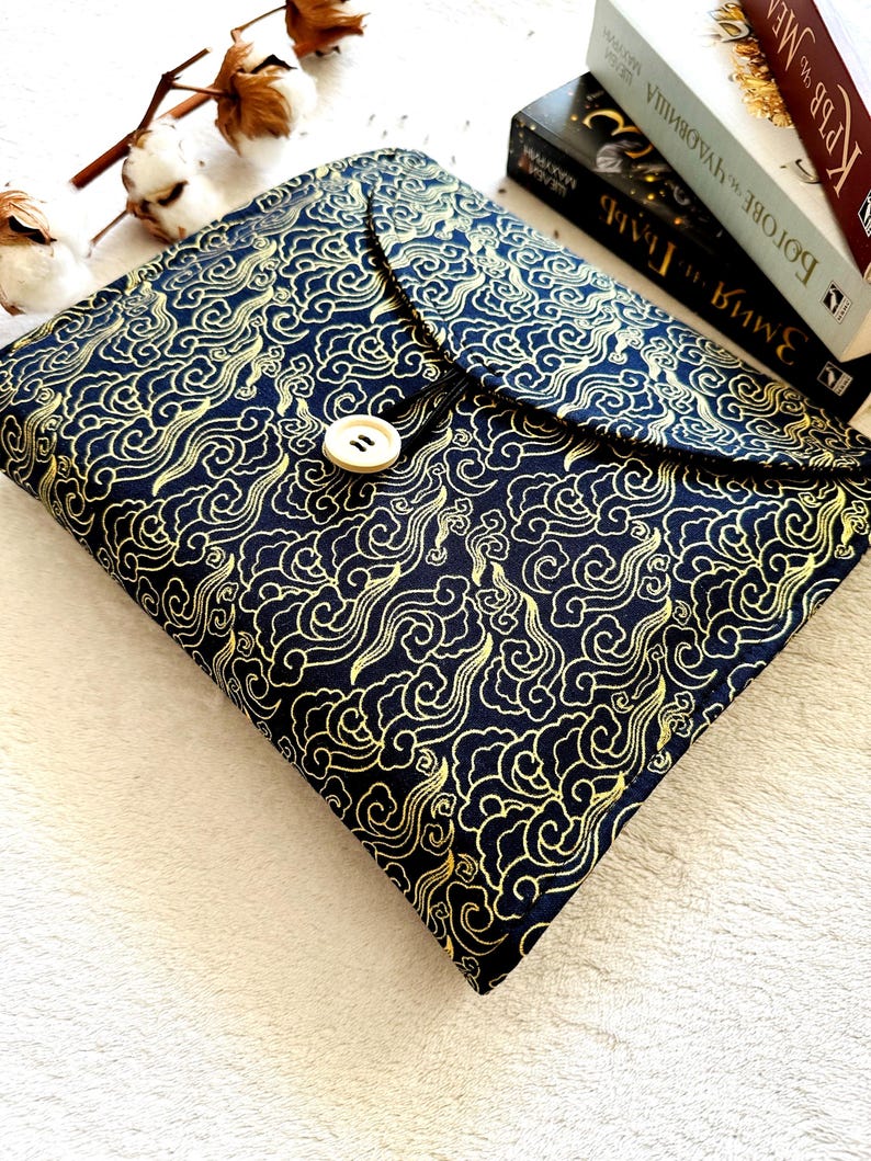 May include: A black fabric book cover with a gold cloud pattern and a single button closure.