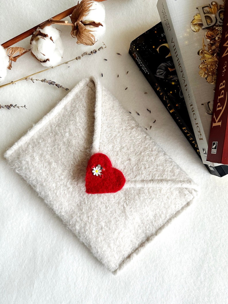 Może przedstawiać: Biała, puszysta koperta z czerwonym sercem z filcu z białym kwiatkiem.