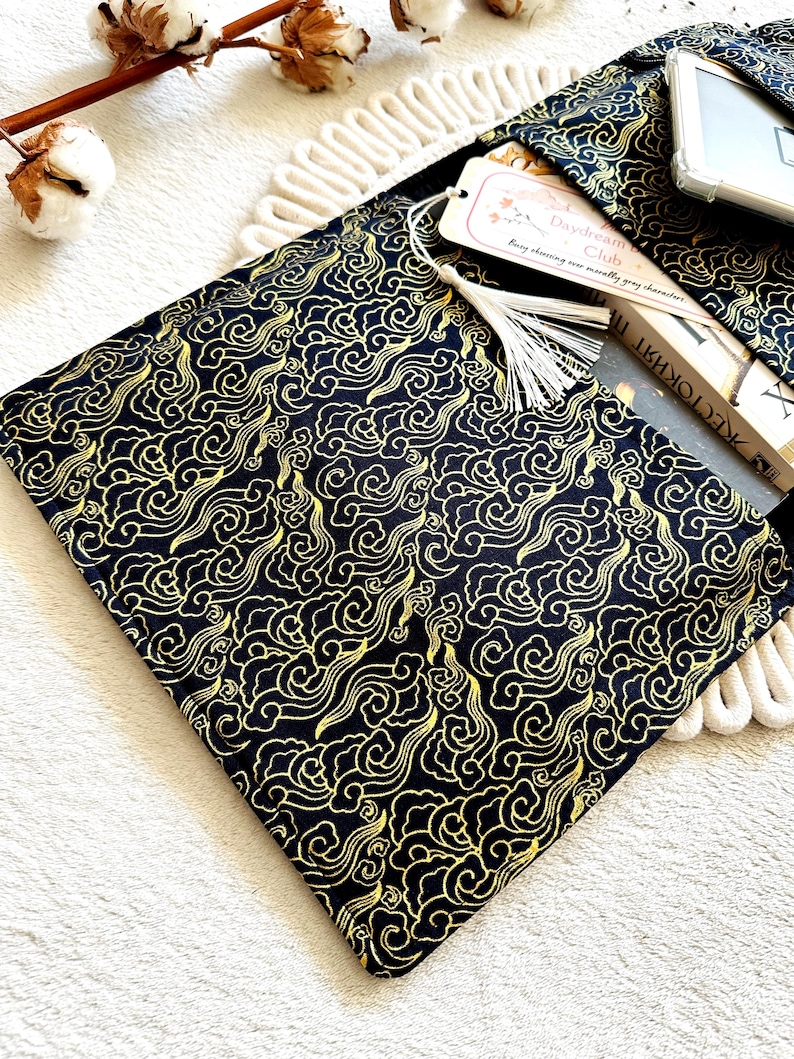 May include: A black fabric book sleeve with a gold cloud pattern. The sleeve has a tassel and a bookmark that says "Daydream Club".