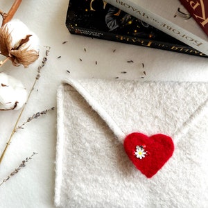 Może przedstawiać: Biała koperta z filcu z czerwonym sercem z filcu i białym kwiatem.