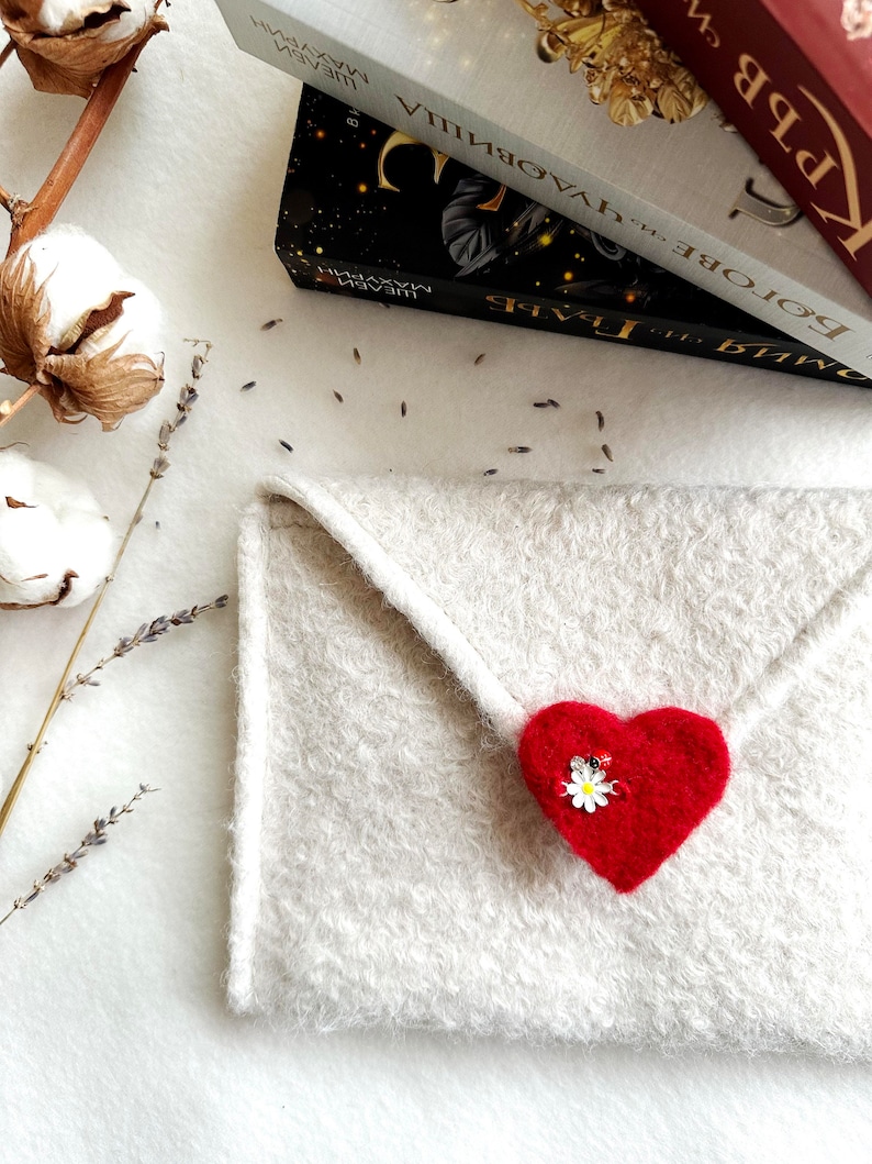 Może przedstawiać: Biała koperta z filcu z czerwonym sercem z filcu i białym kwiatem.